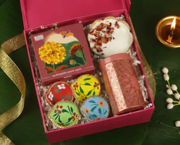 Diwali Festive Gift Box — Diya & Sweets Hamper Close-up of fluorescent Diwali box contents including patterned tea tin and hand-painted clay diyas