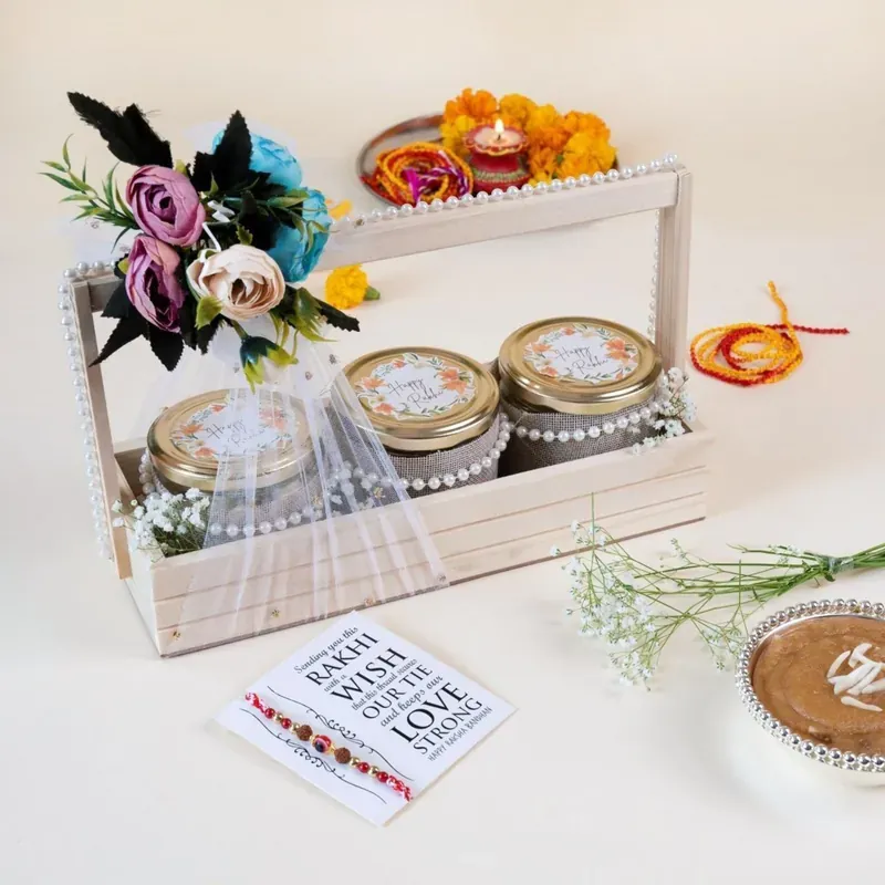 Rakhi Gift Crate — Pinewood Box with Snacks Top angle view of rustic floral pinewood Rakhi gift crate with premium packaging and ribbon